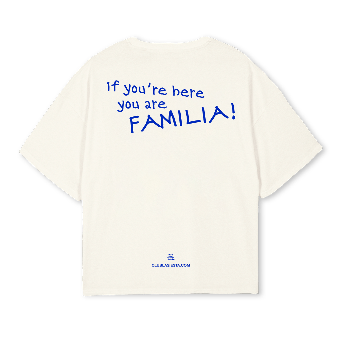 An off-white short-sleeve t-shirt shown from the back, featuring the blue text 'if you're here you are FAMILIA!' printed on the back, with 'CLUBLAJESITA.COM' printed near the bottom hem.