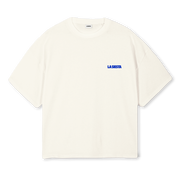 An off-white short-sleeve crewneck t-shirt with 'LA SIESTA' printed in blue text on the left chest, displayed against a solid white background.