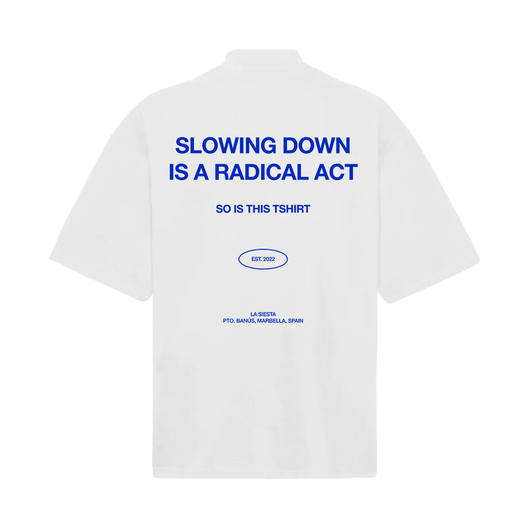 LA SIESTA oversized white mock neck t-shirt with cobalt blue text reading “Slowing Down Is a Radical Act”, back view