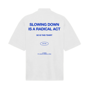LA SIESTA oversized white mock neck t-shirt with cobalt blue text reading “Slowing Down Is a Radical Act”, back view